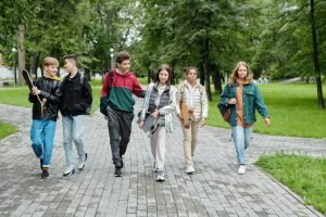 A group of teens walk together in a line, looking happy.